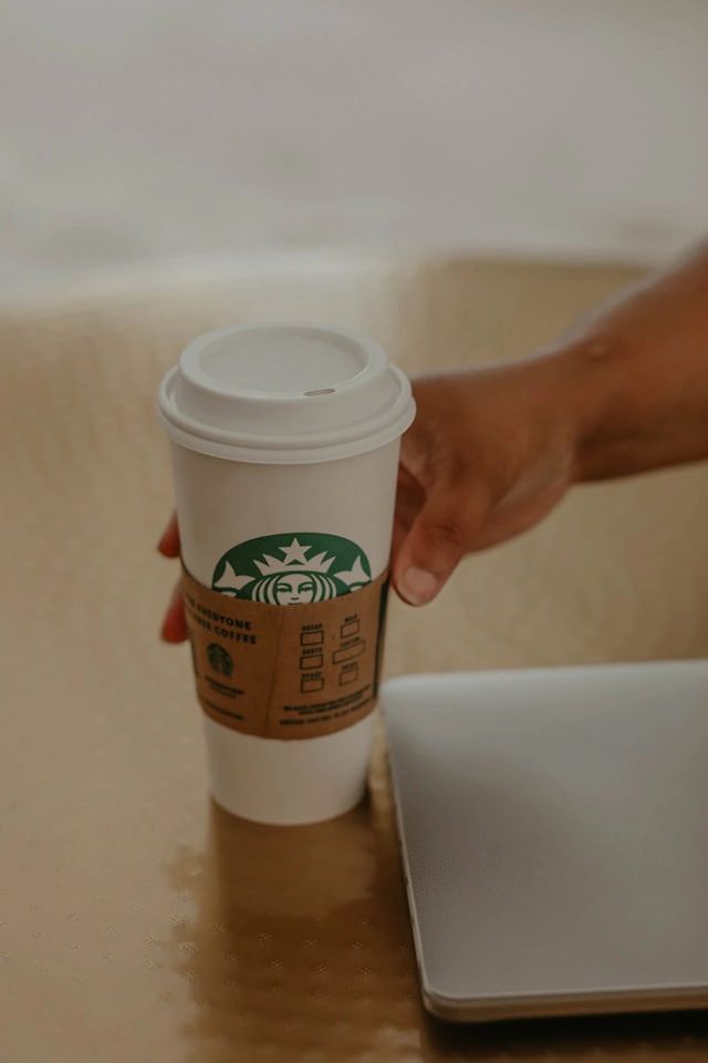 Someone reaching for a Starbucks coffee