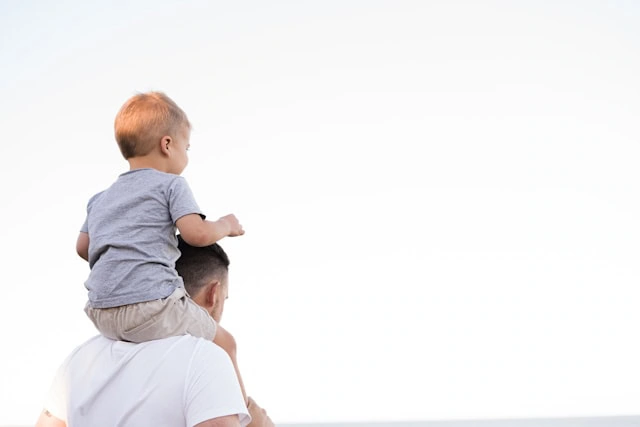 A dad carrying his son